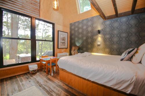 a bedroom with a bed and a desk and windows at Black Mamba House in Harrietville