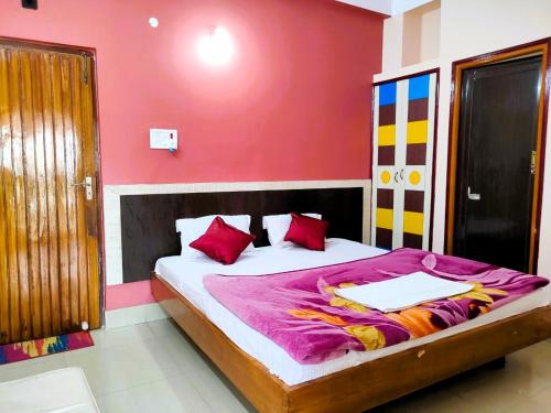 een slaapkamer met een bed met een rode muur bij Hotel Vaishnavi near Baba Dham Temple in Deoghar