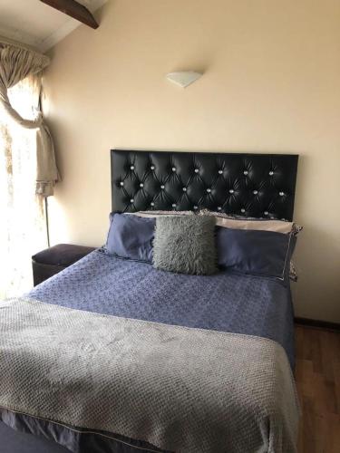 a bedroom with a large bed with a black headboard at Manors' Holiday Home in Durban