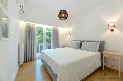 een witte slaapkamer met een groot bed en een raam bij Trendy Living in Koukaki! "Hotspot!" Nighttime noise possible in Athene