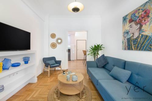 a living room with a blue couch and a tv at Trendy Living in Koukaki! "Hotspot!" Nighttime noise possible in Athens