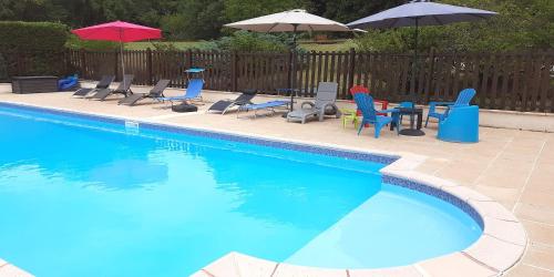 a swimming pool with chairs and tables and umbrellas at Le Bos de Montassot in Savignac-les-Églises