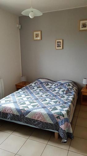 a bedroom with a bed with a quilt on it at Le Bos de Montassot in Savignac-les-Églises