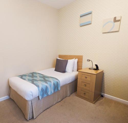 a small bedroom with a bed and a night stand at Biarritz Hotel in St Brelade