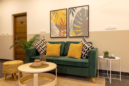 a living room with a green couch and two tables at Olive Domlur - by Embassy Group in Bangalore