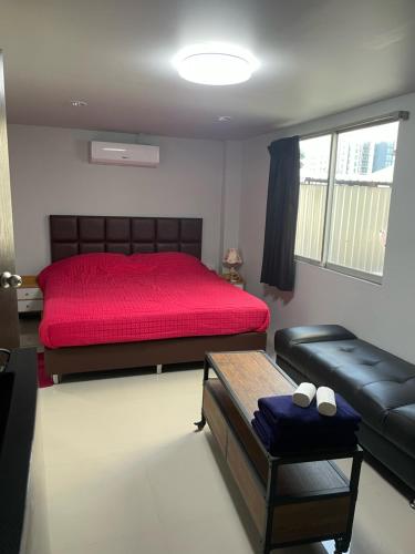 a bedroom with a red bed and a couch at Happy Apple Guesthouse in Pattaya Central