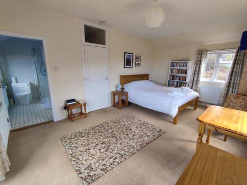a bedroom with a white bed and a bathroom at 3 bed in Scourie SU164 in Rhiconich