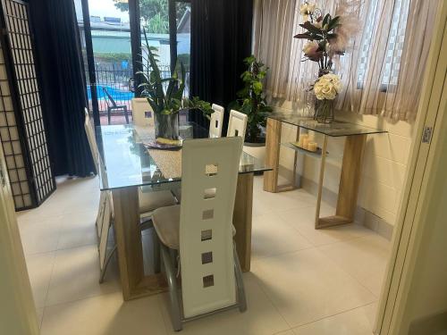 a dining room with a glass table and chairs at Boutique Granny Flat in Paraparap