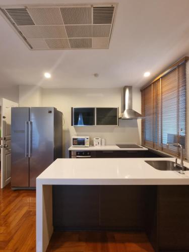 a kitchen with a stainless steel refrigerator and wooden floors at Chez Moi Bangkok Private Executive Residence Sukhumvit 26 in Khlong Toei