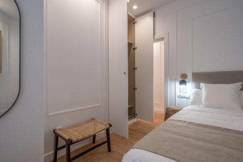 a bedroom with a bed and a stool next to a door at XPCE Cathedral - Luxury Flat in Málaga
