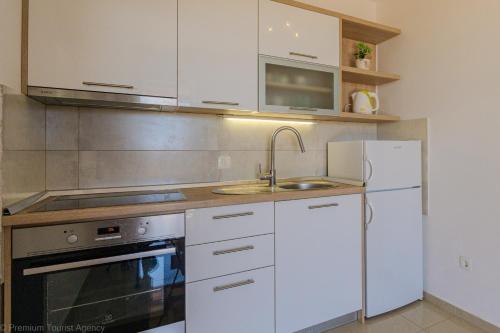 a kitchen with white cabinets and a sink and a refrigerator at Marva stylish Mediterranean accomodation with beautiful view in Zubovići