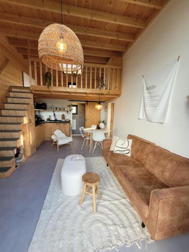 uma sala de estar com um sofá e uma mesa em NEW! Tiny House Lantliv Oostkapelle, bij de boer em Oostkapelle