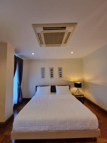 a bedroom with a large white bed with a ceiling at Chez Moi Bangkok Private Executive Residence Sukhumvit 26 in Khlong Toei