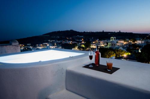 a bottle of wine and two glasses on a ledge with a pool at The Luna Suite with jacuzzi in Emporio