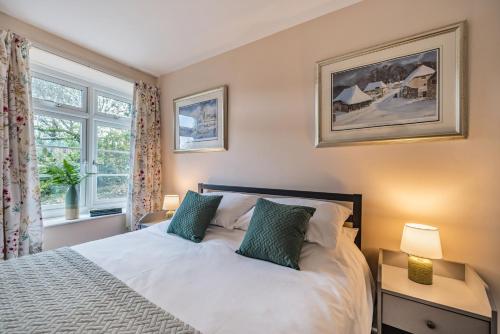 a bedroom with a bed with two lamps and a window at Ivy Cottage in Buckland in the Moor