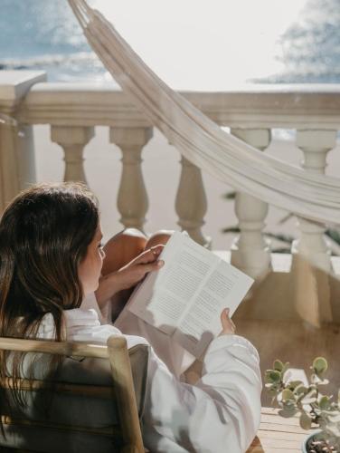 a woman sitting in a chair reading a book at Voramar in Benicàssim