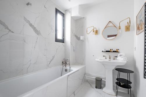 La salle de bains blanche est pourvue d'une baignoire blanche et d'un lavabo. dans l'établissement Veeve - Spire View, à Paris