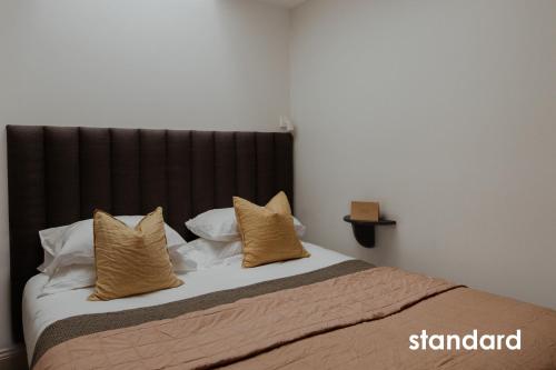 a bed with a black headboard and pillows at HIDEOUT Hotel in Hull