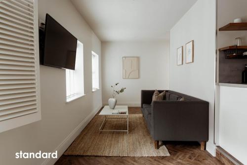 a living room with a couch and a flat screen tv at HIDEOUT Hotel in Hull