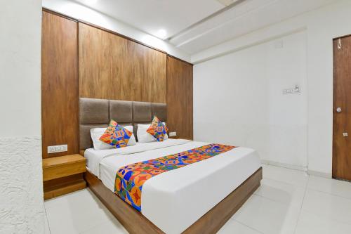 a bedroom with a large bed with a wooden headboard at FabHotel Maan Palace in Naroda