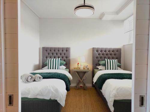 sypialnia z 2 łóżkami z zieloną i białą pościelą w obiekcie Brizzy's Balcony A Well-located Luxe Retreat w mieście South End