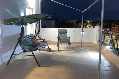 two chairs and an umbrella on a balcony at night at Rooftop Acropolis Apartment Athens in Athens