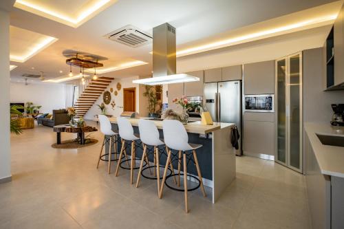 a kitchen and living room with a bar with white stools at Villa Manglar in Las Terrenas
