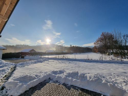 a snow covered yard with the sun in the background at Casa Guzinni in Písečná