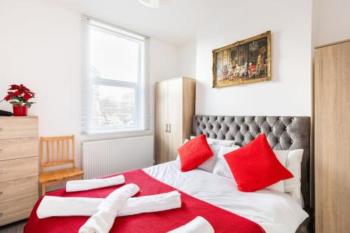 a bedroom with red and white pillows on a bed at Parkside Stay North London - Victoria Line in London