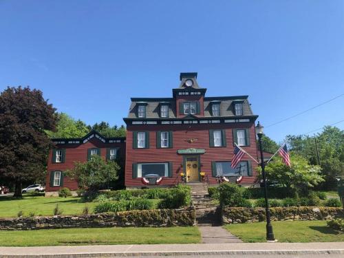 a large red house with two american flags in front of it at Elegant 2BR Apt w 2 Bathrooms in Historic Hamlet by Berkshires & Hudson Valley, Walk to Restaurants in Hillsdale