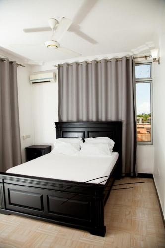 um quarto com uma cama com lençóis brancos e uma janela em MIKOCHENI APARTMENT em Dar es Salaam