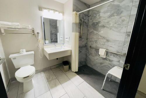 y baño con aseo, lavabo y ducha. en Super 8 by Wyndham Shakopee, en Shakopee