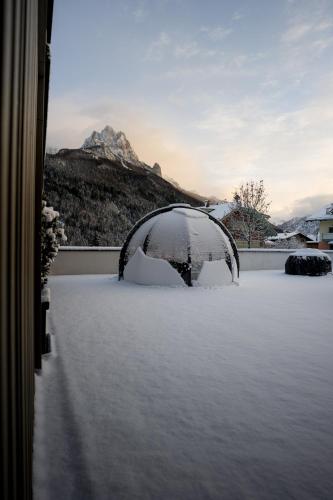a snow covered yard with a view of a mountain at DOLOMITI EXCLUSIVE YOUR MOUNTAIN SUITE in Pozza di Fassa