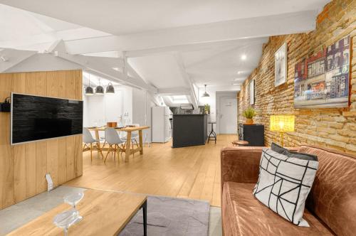 un salon avec un canapé et un mur de briques dans l'établissement Le Brandy - Charmant loft climatisé de 42m², à Toulouse