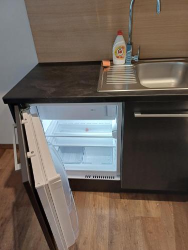 an open refrigerator in a kitchen next to a sink at Apartmán 107 Ovruč in Štrbské Pleso