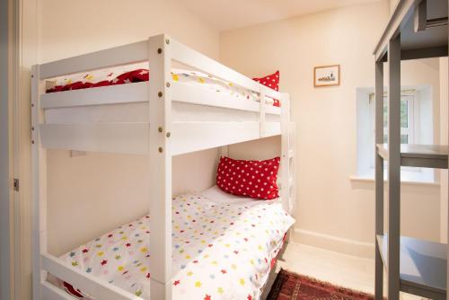 a bunk bed in a childs room with red pillows at The Bothy at Redheugh in Newcastleton