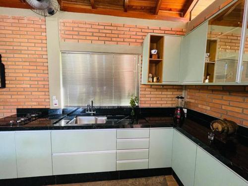 a kitchen with a sink and a brick wall at Casinha charmosa e muito verde em Bom Princípio in Toledo
