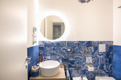 Baño de azulejos azules con lavabo y espejo en Blue Vert Maison - al molo di Gaeta, en Gaeta