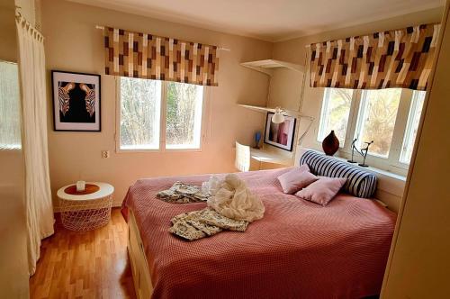 a bedroom with a bed with red sheets and windows at Villa Tullinge - for work or vacation in Tullinge