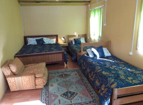 1 dormitorio con 2 camas, sofá y silla en Beautiful cabin in Patagonia Chile., en Chile Chico