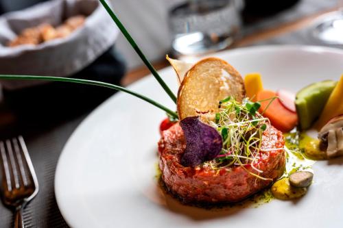 a white plate with a piece of meat and vegetables at Hotel Restaurant Bänklialp in Engelberg