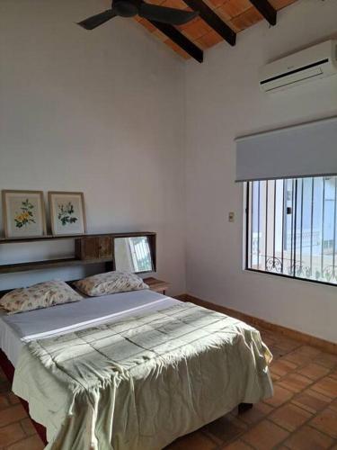 - une chambre avec un lit dans une pièce dotée d'une fenêtre dans l'établissement Casa colonial a metros del arroyo, à Piribebuy