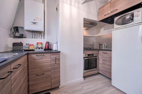 a kitchen with wooden cabinets and a white refrigerator at Villepinte, 2-4 pers, proche aéroport Roissy CDG, parc des expositions, Disney in Villepinte