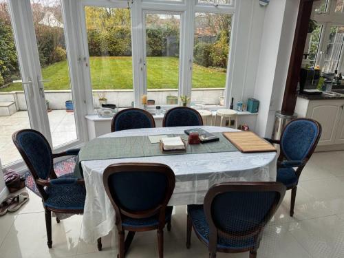 a dining room with a table and chairs and windows at Cosy and lovely 4-Bed House in Stanmore in Stanmore