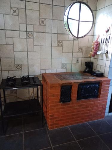 a kitchen with a brick stove and a table at Chácara Sensorial Nova Friburgo RJ in Nova Friburgo