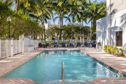 a swimming pool with palm trees in the background at Hampton Inn West Palm Beach Central Airport in West Palm Beach