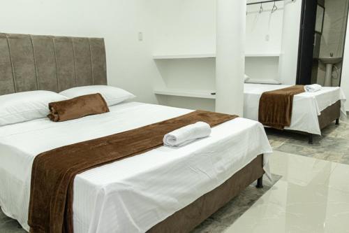 two beds in a hotel room with towels on them at Hotel Maranta in Pereira