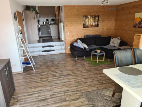 a living room with a black couch and a kitchen at NEU Ferienwohnung im Nationalpark Bayrischer Wald in Neukirchen