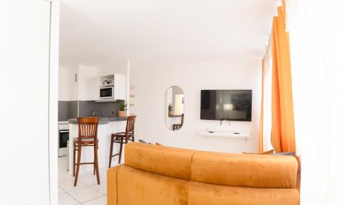 un salon avec un canapé et une cuisine dans l'établissement Élégant Studio proche de Paris et Disneyland, à Villemomble