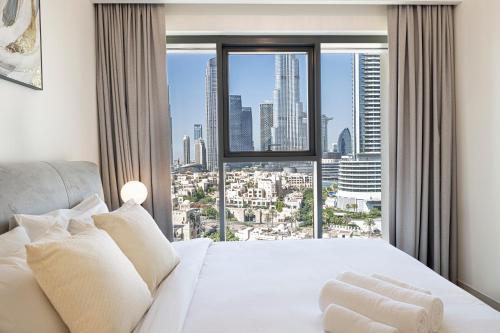 a bedroom with a white bed with a large window at FirstStay Homes - Burj Royale Residences Downtown Dubai - Burj Khalifa District in Dubai
